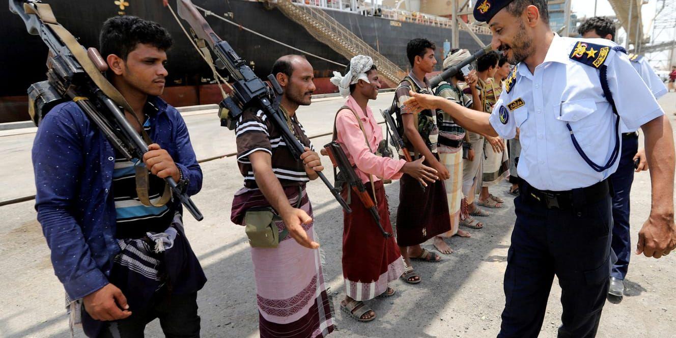 Huthirebeller vid överlämningen av hamnen i Salif i Jemen skakar hand med ett befäl från kustbevakningen – som enligt regeringssidan är en utklädd rebell.