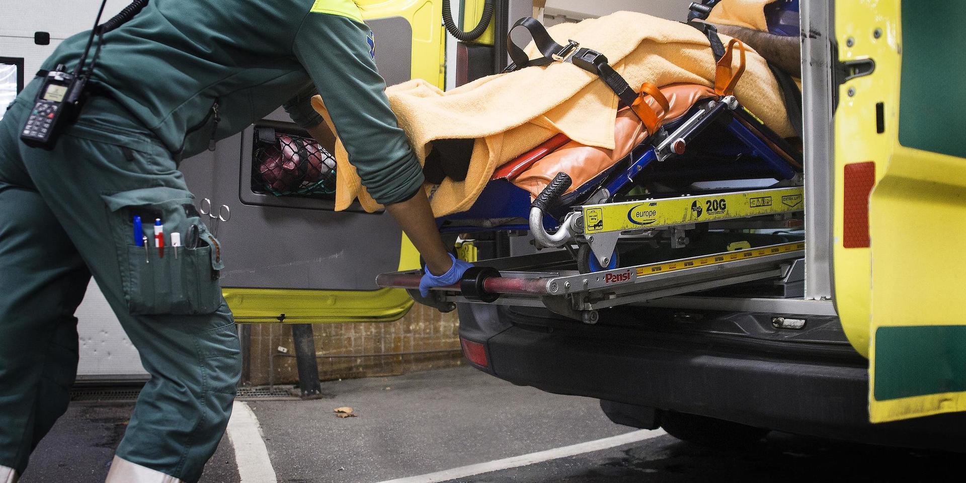 Kvinnlig ambulanssjukvårdare med patient på bår i ambulans.