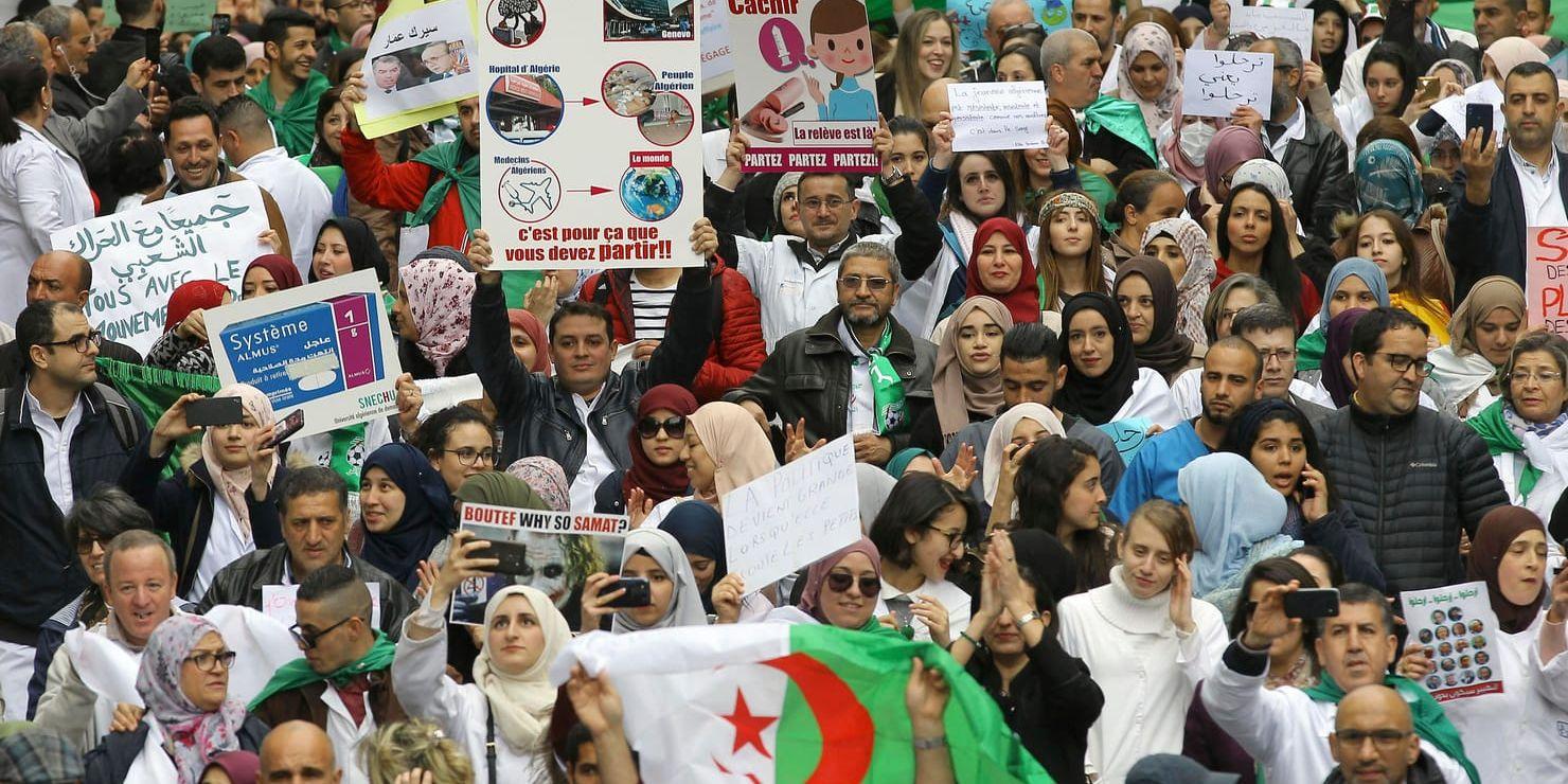 Människor demonstrerar med skyltar och flaggor under en protest i Algeriets huvudstad Alger, med krav på president Abdelaziz Bouteflikas avgång.