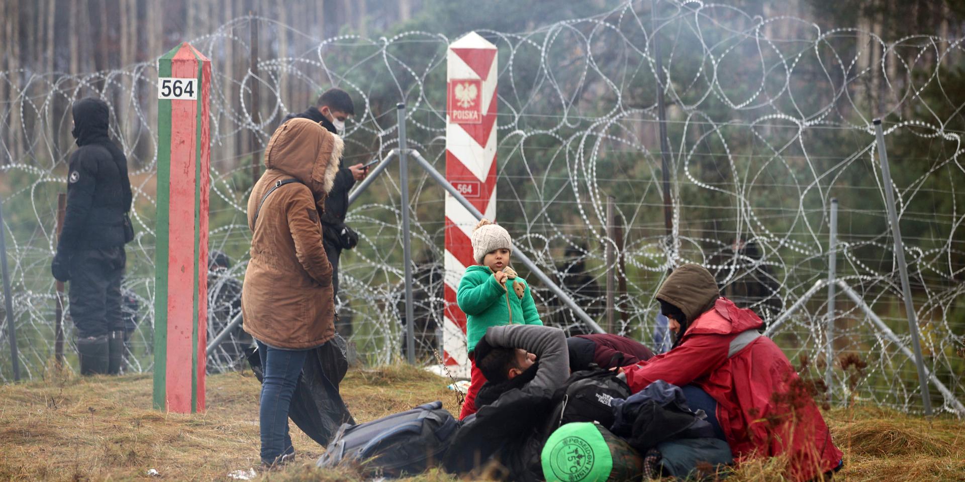 Migrants from the Middle East and elsewhere rest as they gather at the Belarus-Poland border near Grodno, Belarus, Monday, Nov. 8, 2021. Poland increased security at its border with Belarus, on the European Union's eastern border, after a large group of migrants in Belarus appeared to be congregating at a crossing point, officials said Monday. The development appeared to signal an escalation of a crisis that has being going on for months in which the autocratic regime of Belarus has encouraged migrants from the Middle East and elsewhere to illegally enter the European Union, at first through Lithuania and Latvia and now primarily through Poland. (Leonid Shcheglov/BelTA via AP)