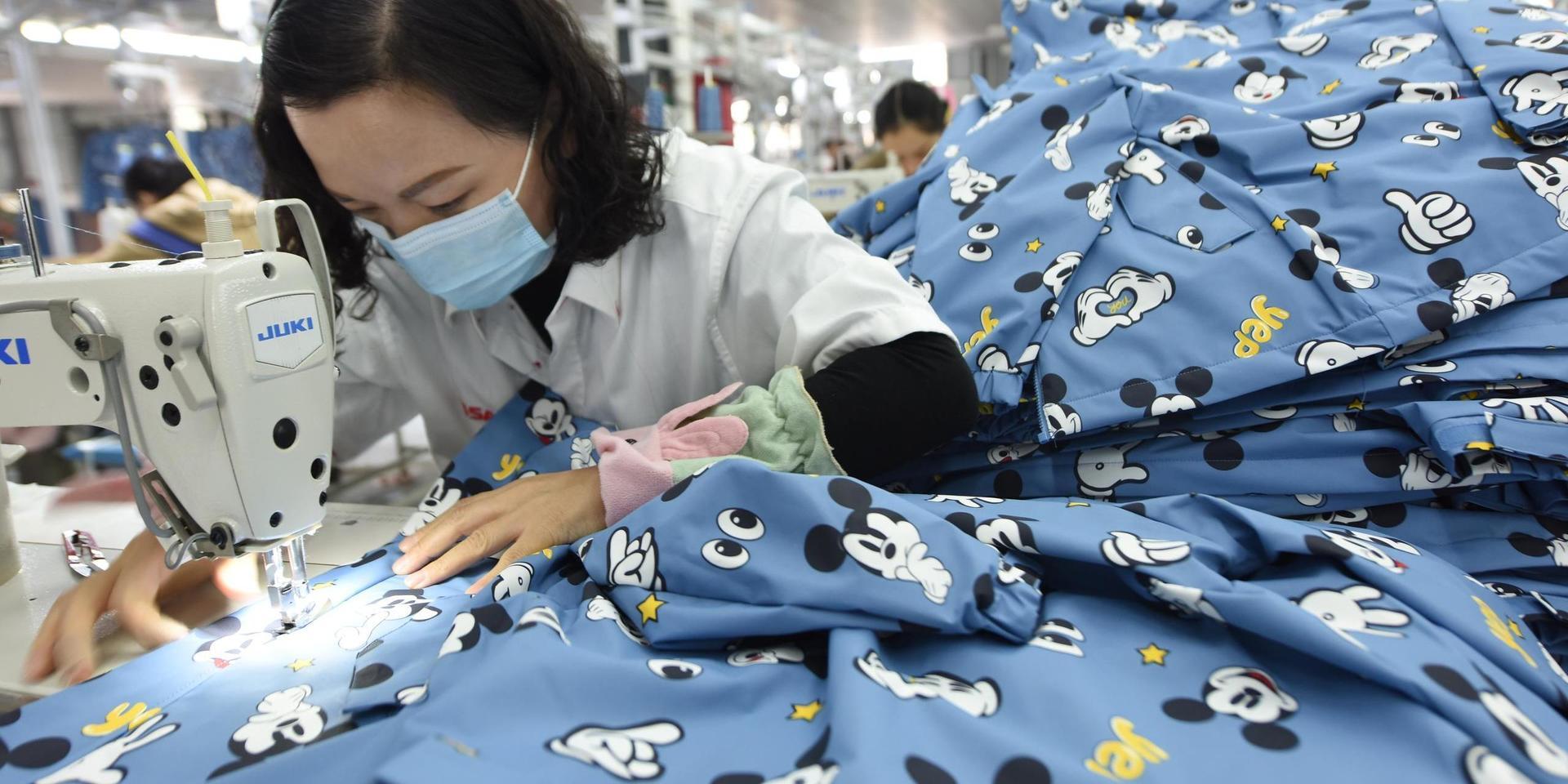 En kinesisk kvinna syr kläder i en fabrik.