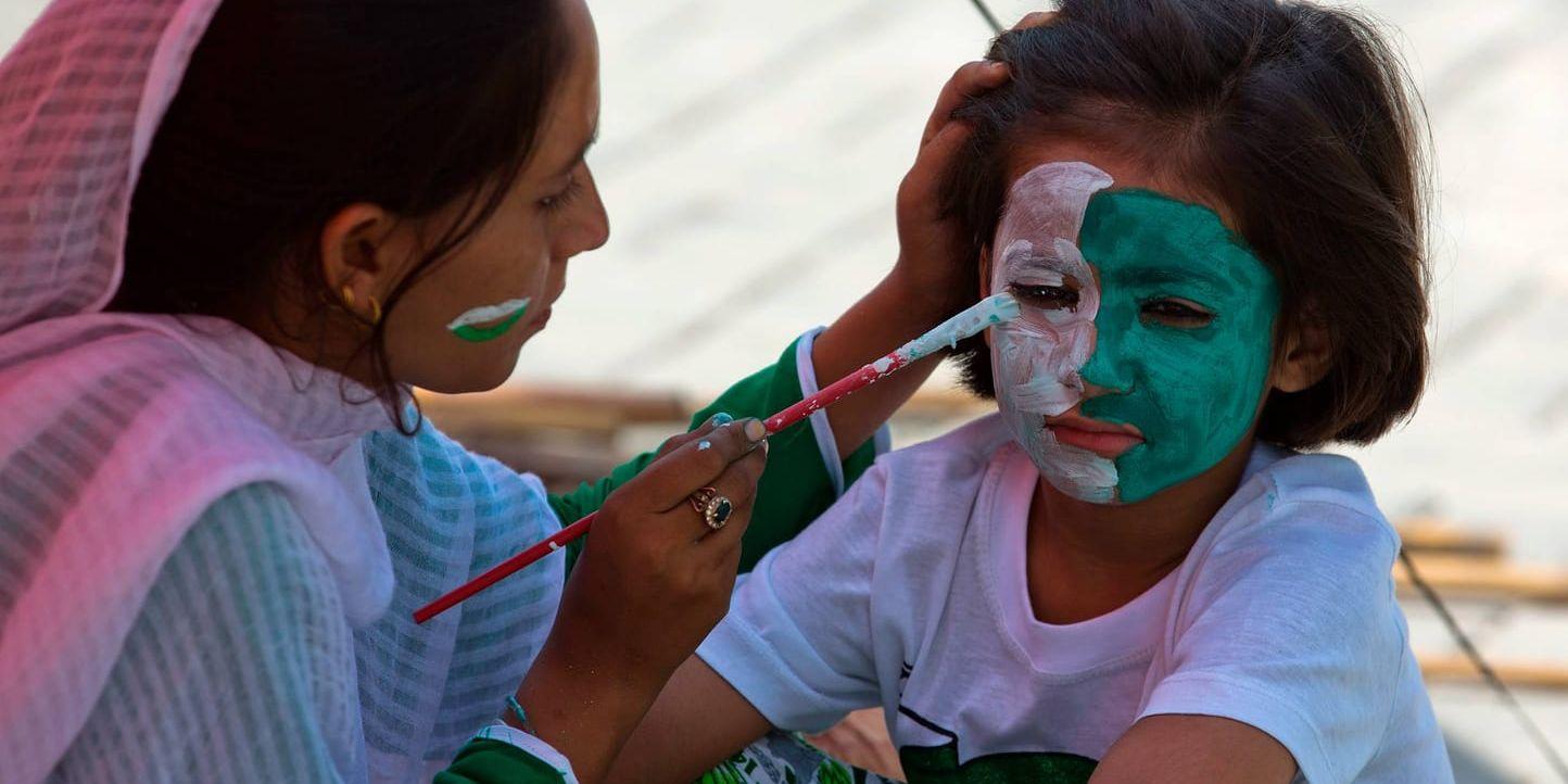 En försäljare målar den pakistanska flaggans färger i ansiktet på en flicka under firandet av landets 70:e självständighetsdag i Rawalpindi i Pakistan.