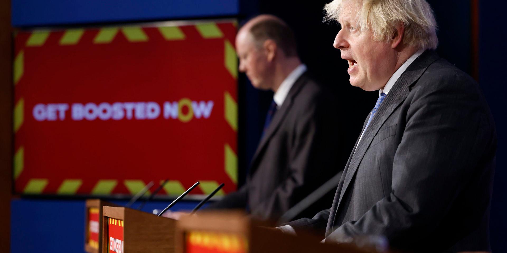 Boris Johnson (närmast kameran) och Chris Whitty på en presskonferens i förra veckan. Skylten uppmanar britterna att ta en tredje vaccinspruta.