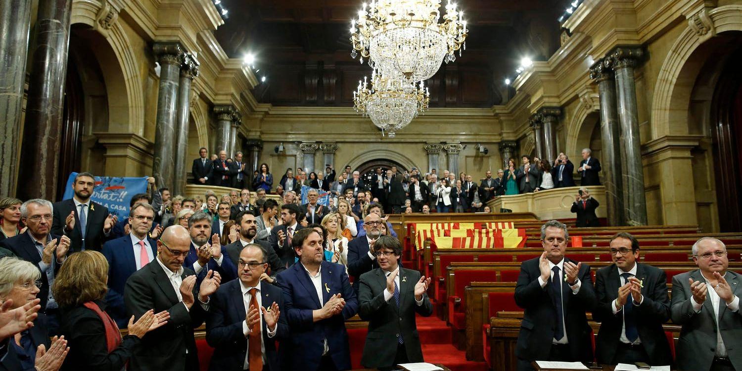 Kataloniens regionpresident Carles Puigdemont, i mitten, applåderar efter det att det katalanska parlamentet röstat igenom resolutionen om självständighet. Oppositionens bänkar gapar tomma, de lämnade salen i protest.