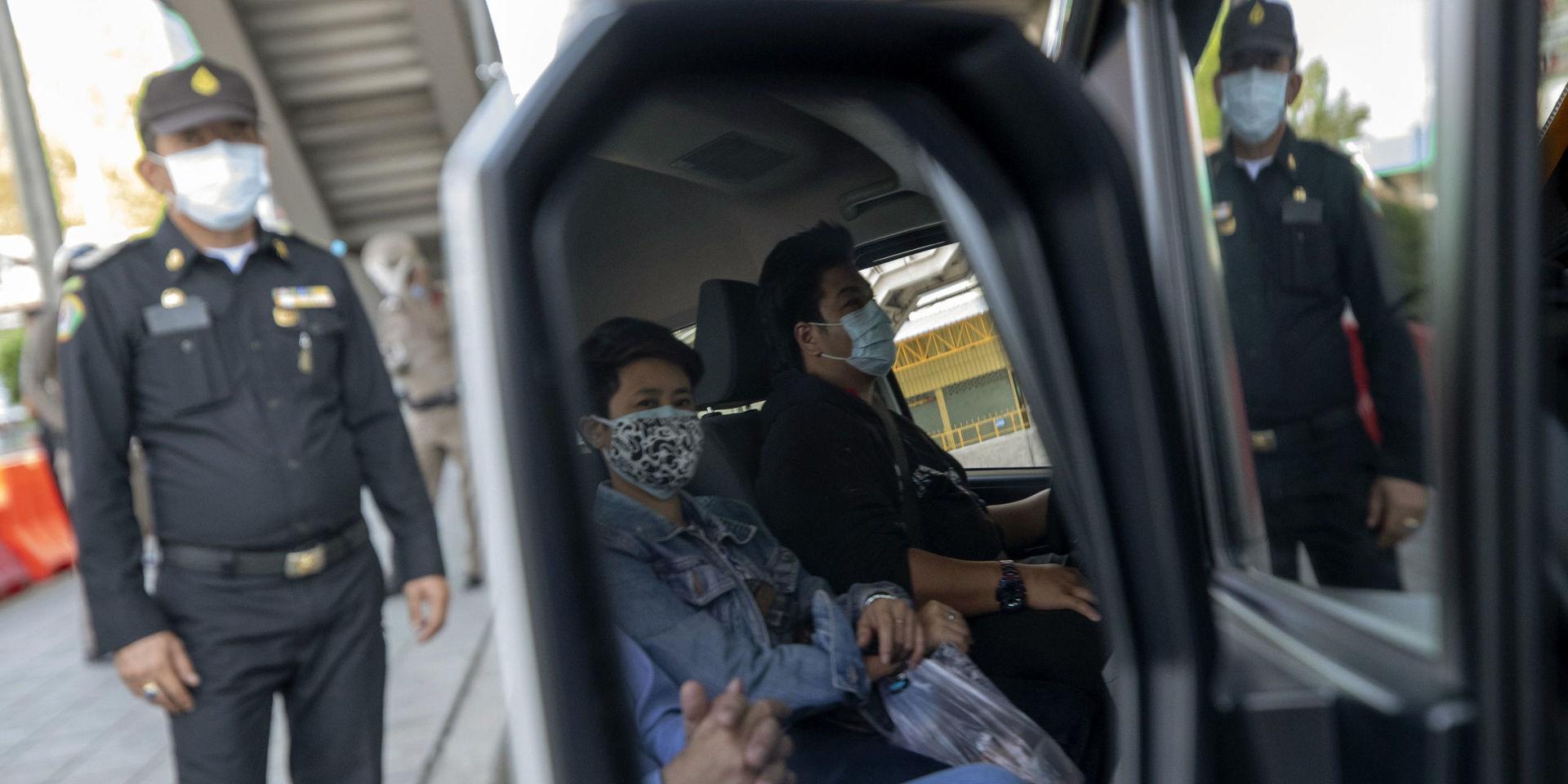 En polis stannar ett fordon i Bangkok för att kontrollera att förare och passagerare inte har feber. 