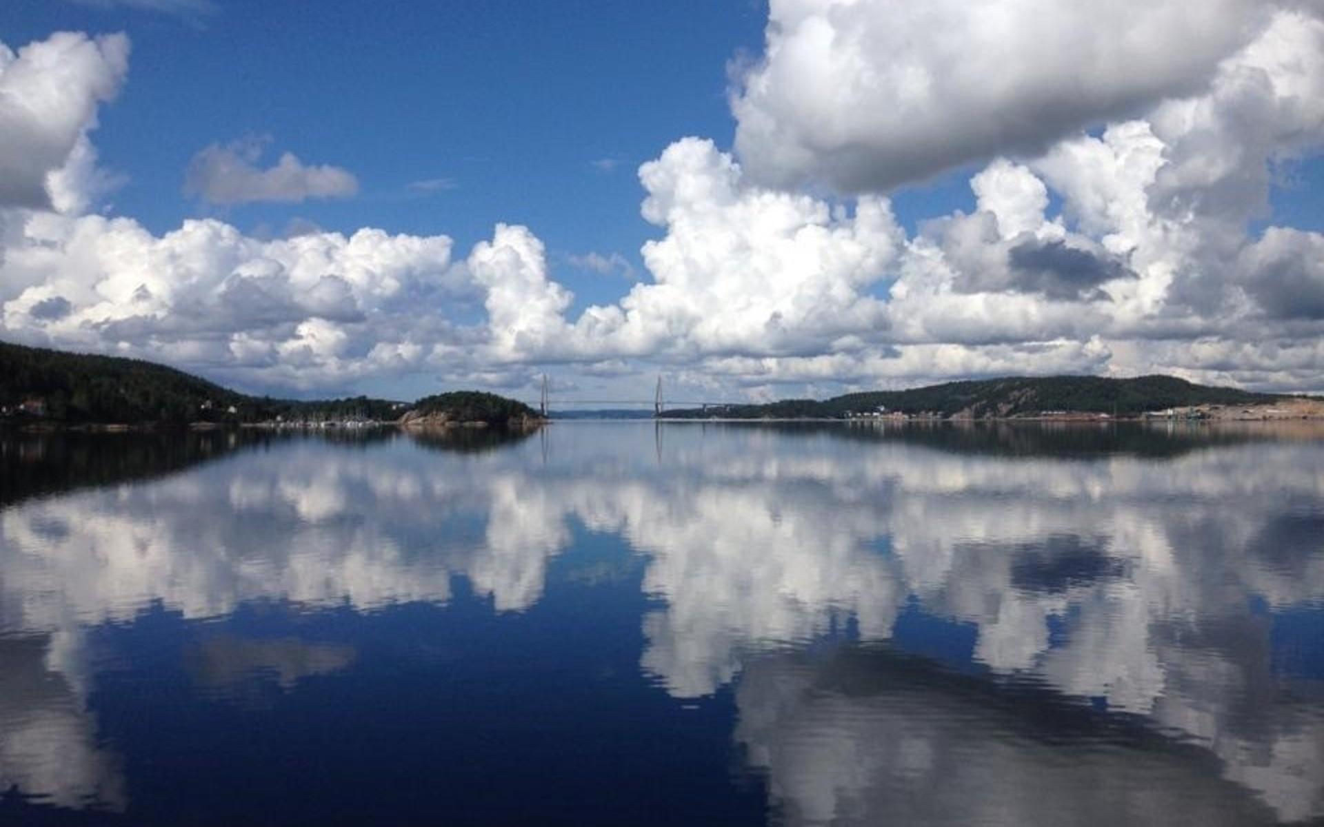 ”Uddevalla vid strandpromenaden. Man ser en skymt av bron. 4/7 -21 en fin sommar dag med spegelblankt vatten , Uddevalla visar en av sina många fina sidor.”