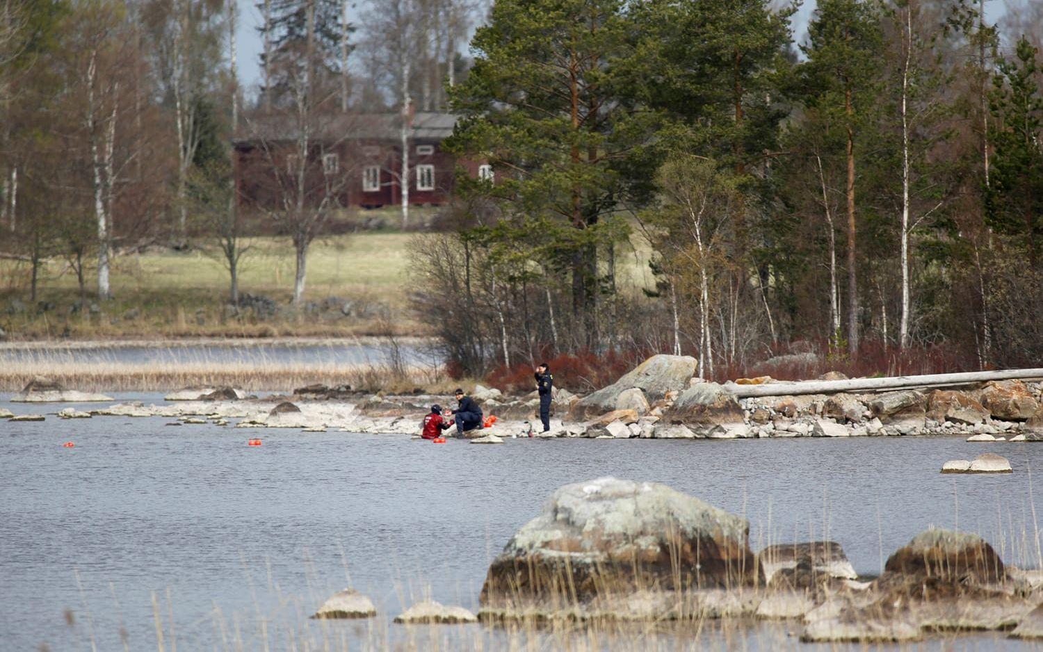 Polisens dykare söker i sjön i närheten av den avspärrade gården. FOTO: TT

