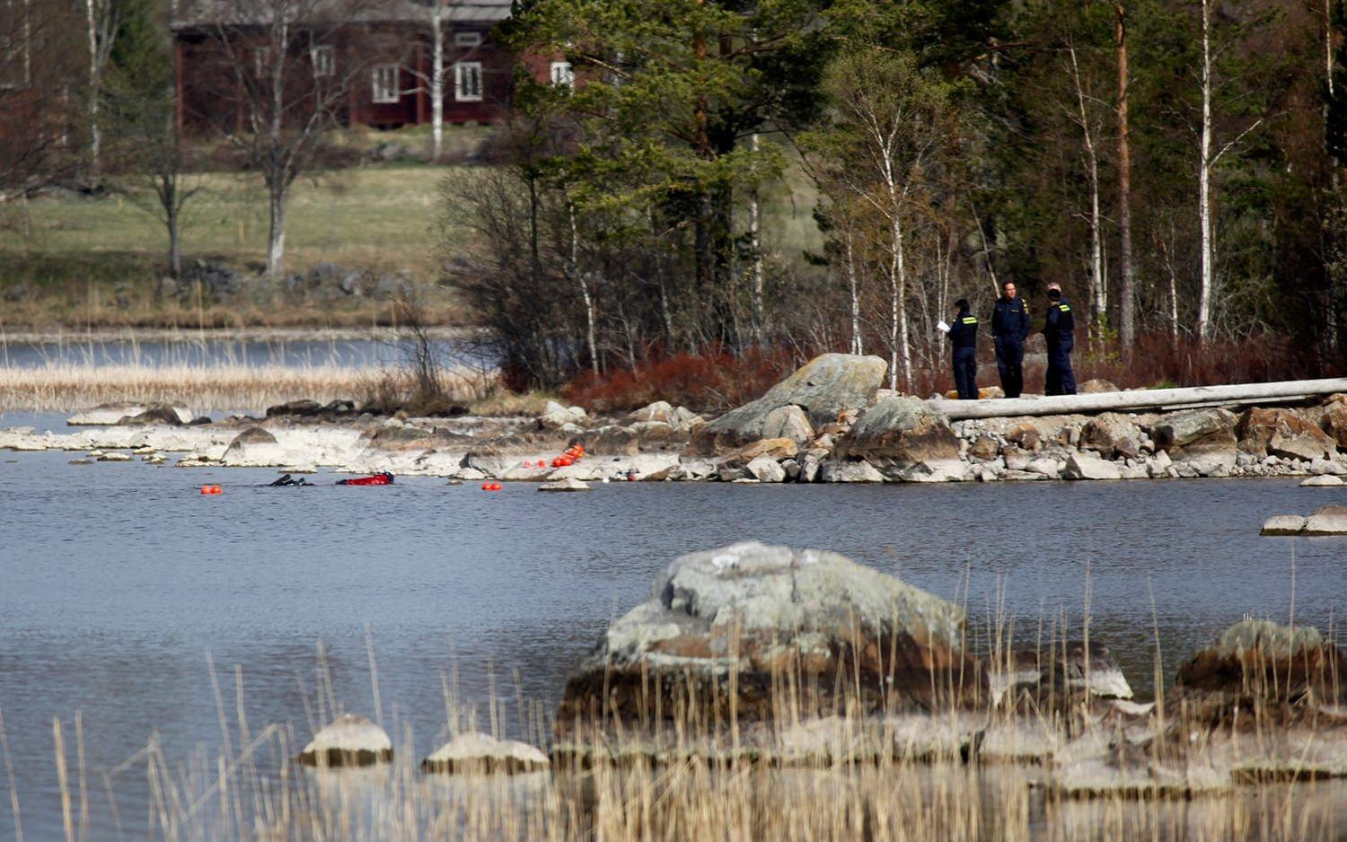 Polisens dykare söker i sjön i närheten av den avspärrade gården. FOTO: TT
