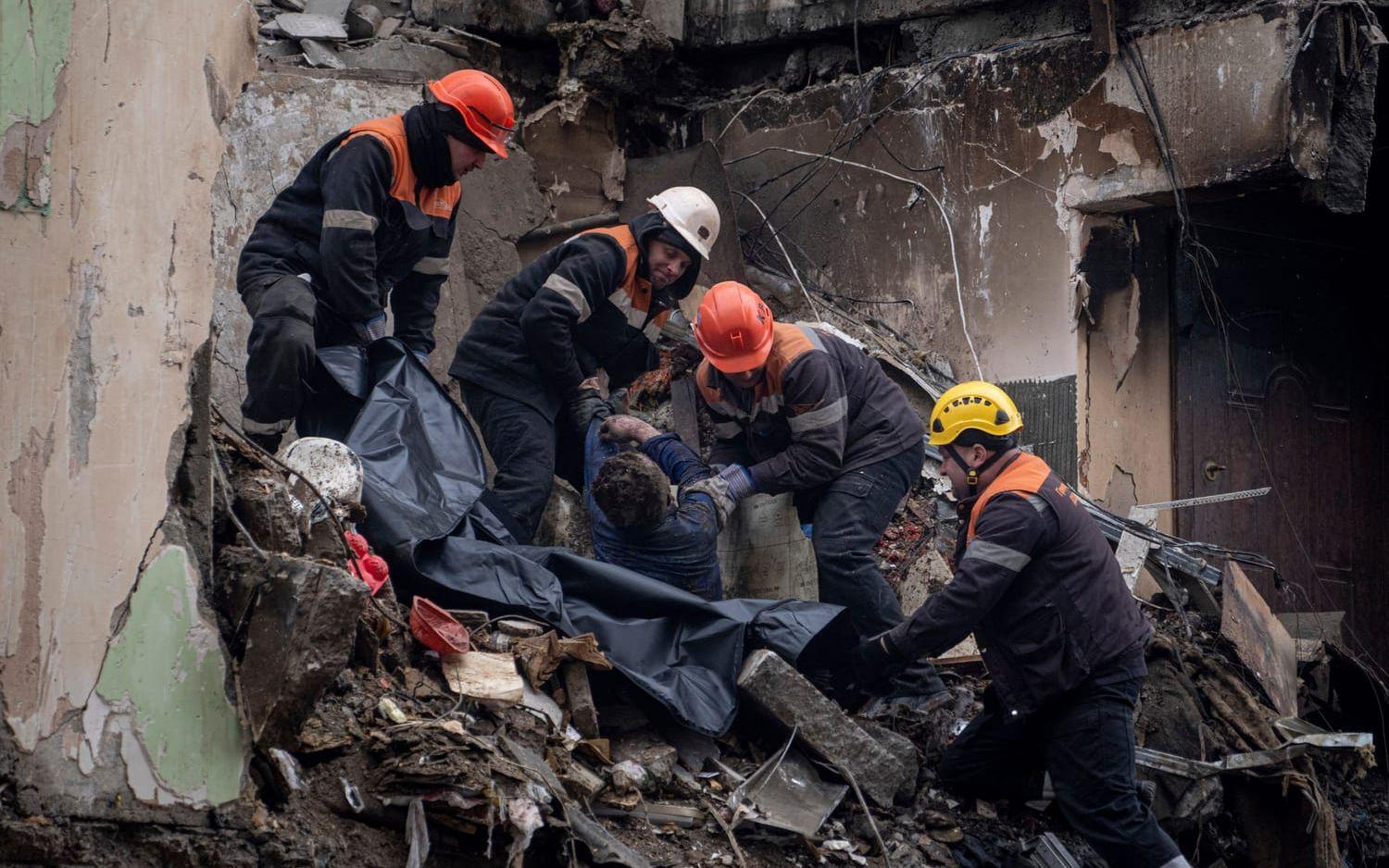 Rescue workers transfer the body of a man killed in a Russian missile strike on an apartment building, into a plastic bag in the southeastern city of Dnipro, Ukraine, Monday, Jan. 16, 2023. (AP Photo/Evgeniy Maloletka)  MAL103