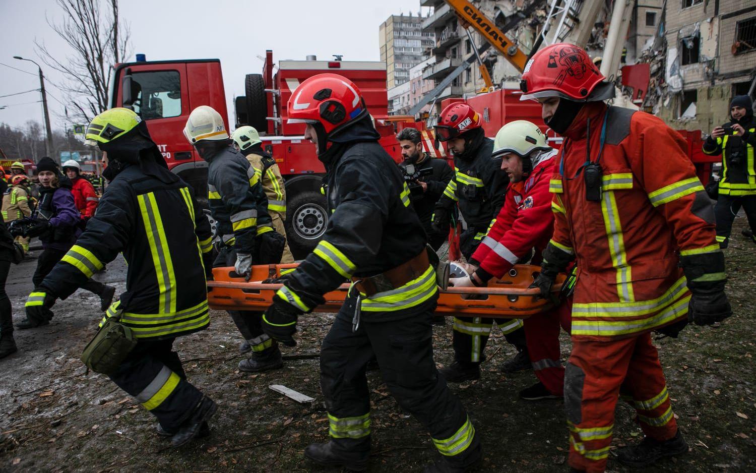 Emergency workers carry a wounded woman after a Russian rocket hit a multistory building  on Saturday in Dnipro, Ukraine, Sunday, Jan. 15, 2023. (AP Photo/Yevhenii Zavhorodnii)  XEL101