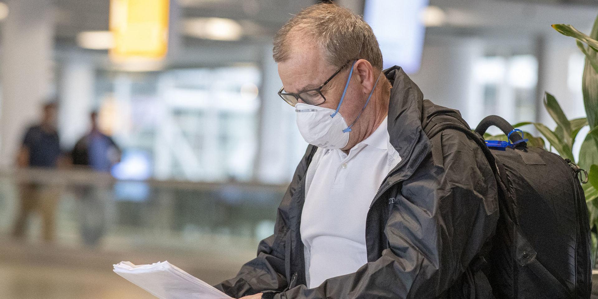 Man på flygplats som använder skyddsmask. 