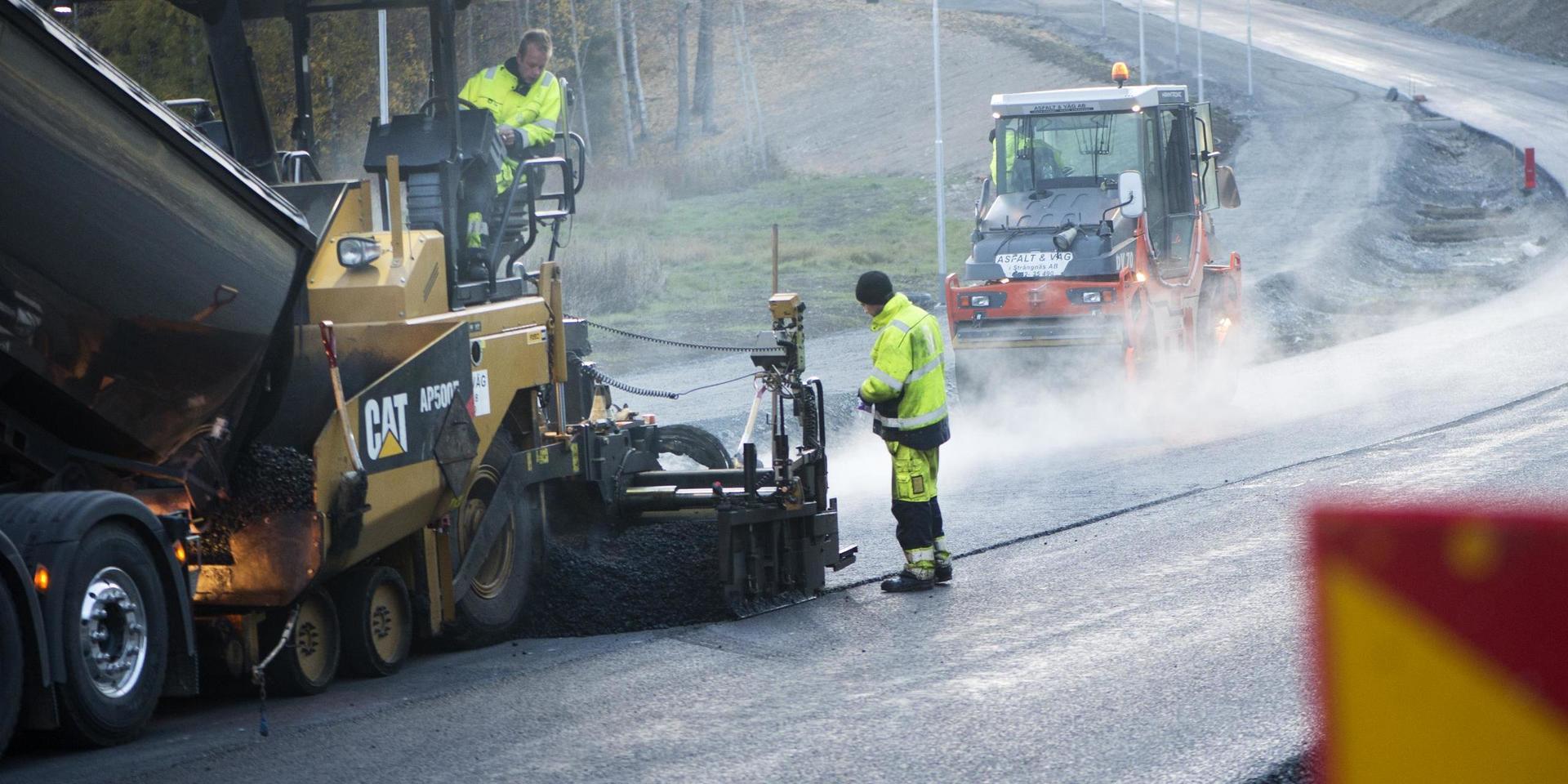 ENKÖPING 20131016Väg- och anläggningsarbetare arbetar på en ny väg. En vägvält (th) plattar till asfalten.Foto: Fredrik Sandberg / TT / Kod 10180