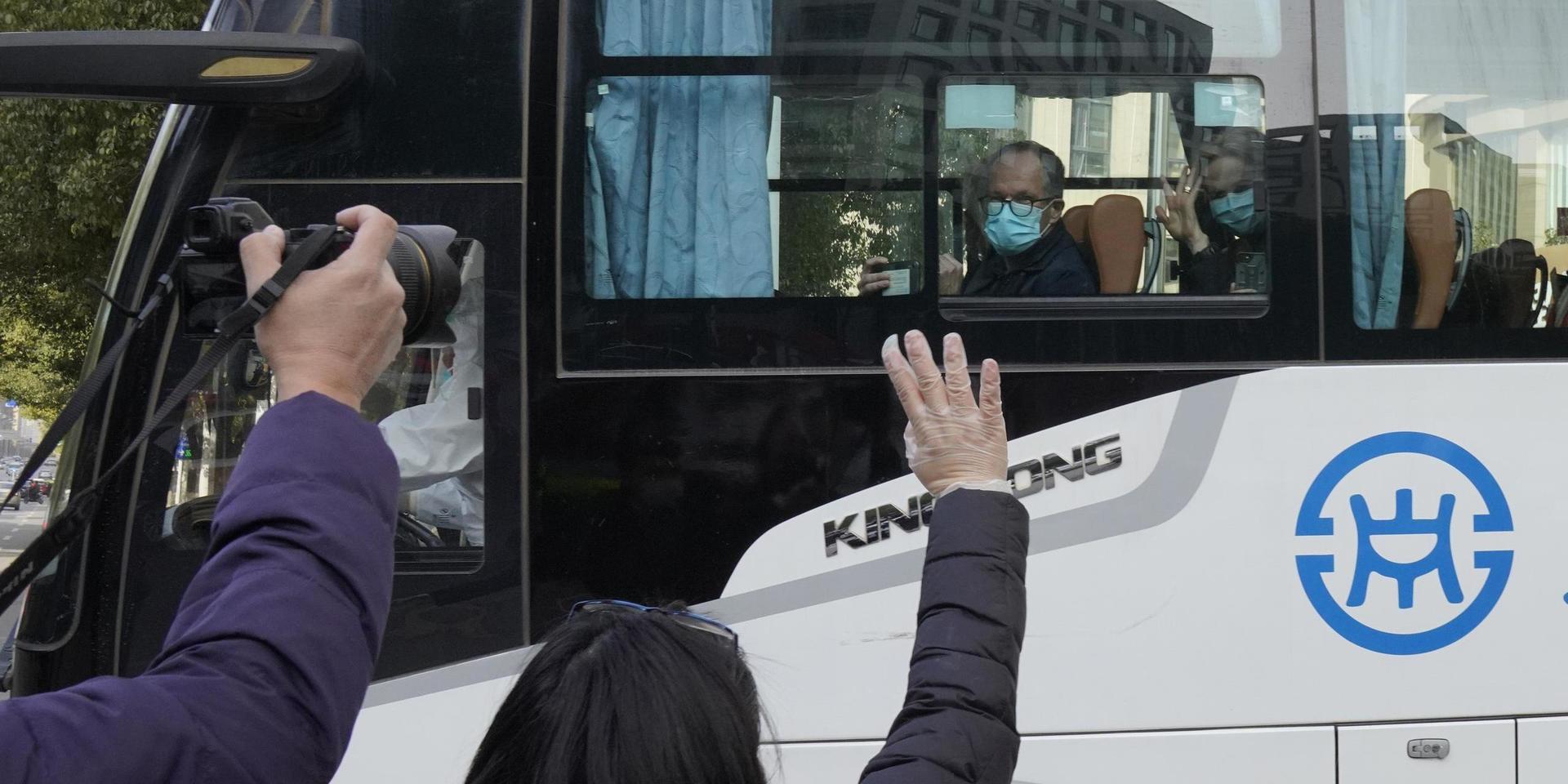 Människor vinkar till WHO:s experter som nu har fått lämna karantänhotellet i Wuhan.
