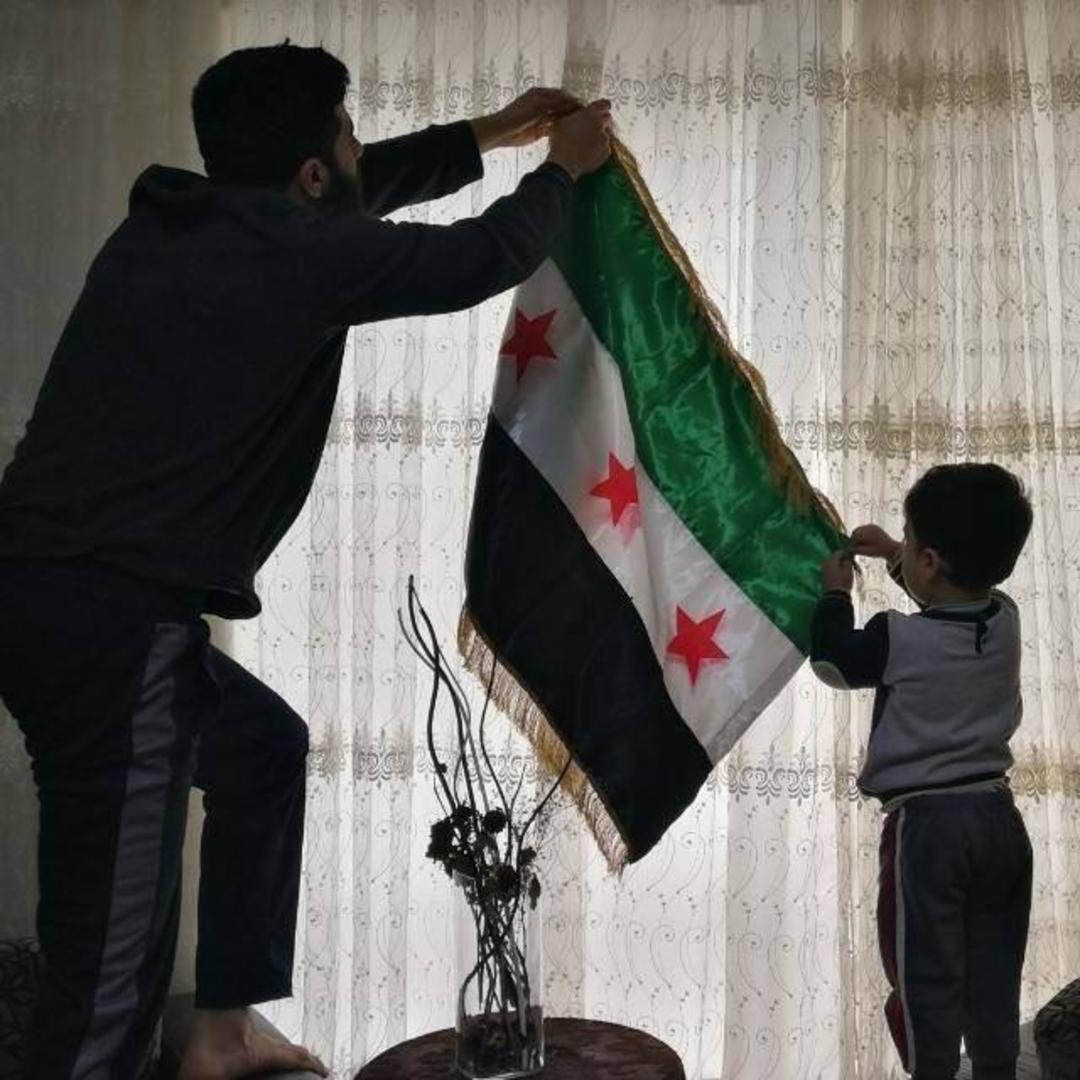 Monther Etaky hänger upp den syriska självständighetsflaggan i Aleppo 2016.