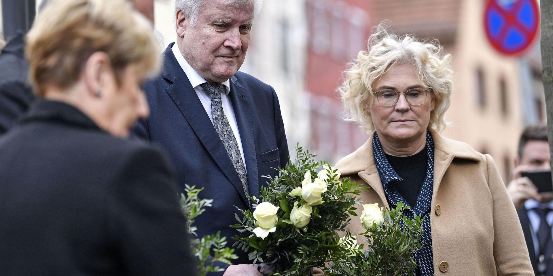 Tysklands inrikesminister Horst Seehofer, i mitten, och justitieminister Christine Lambrecht, till höger, lägger ner blommor utanför ett av de kaféer där flera människor dödades i onsdags. 