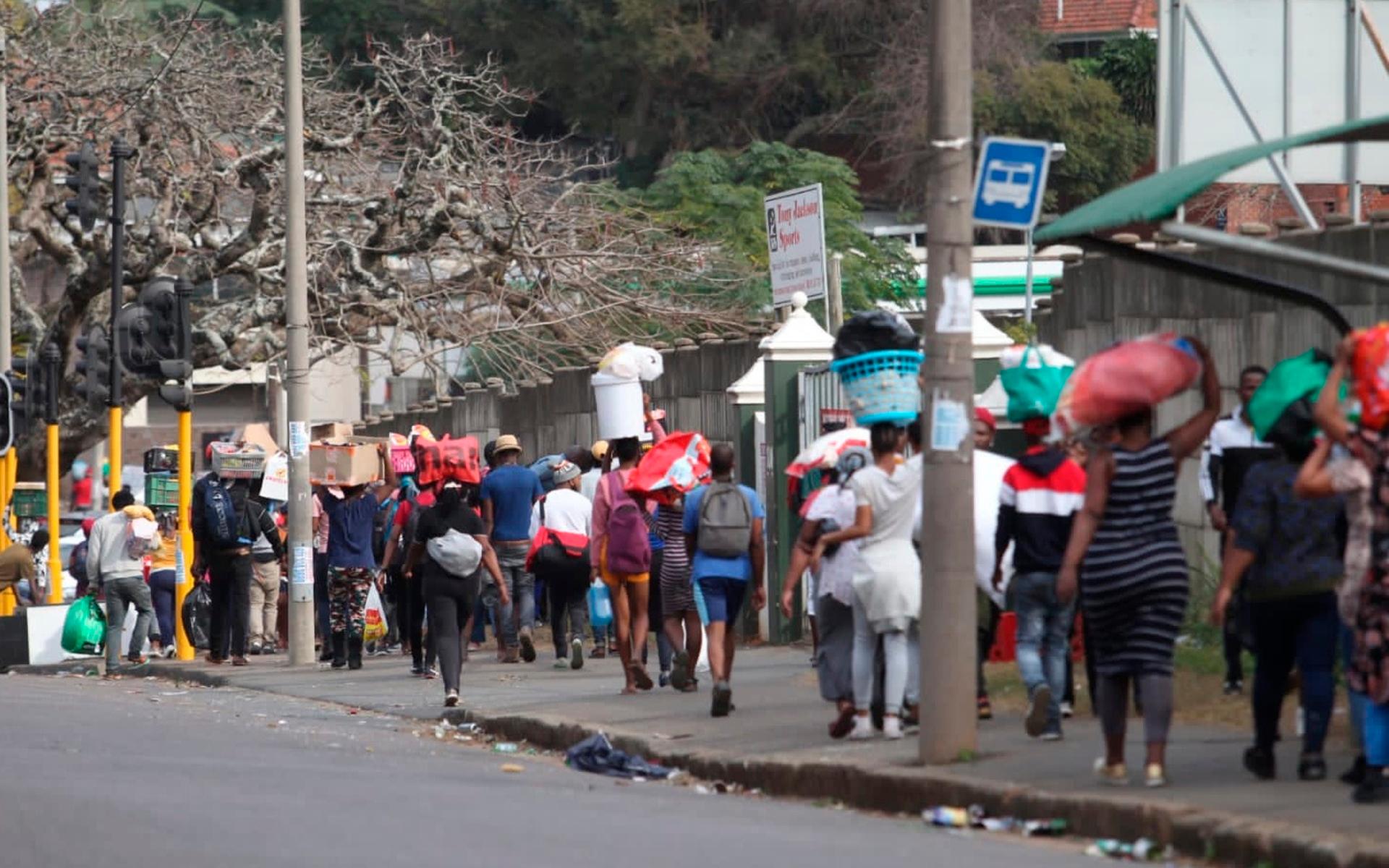 Här går ett flertal personer med gods från ett köpcentrum i staden Durban.