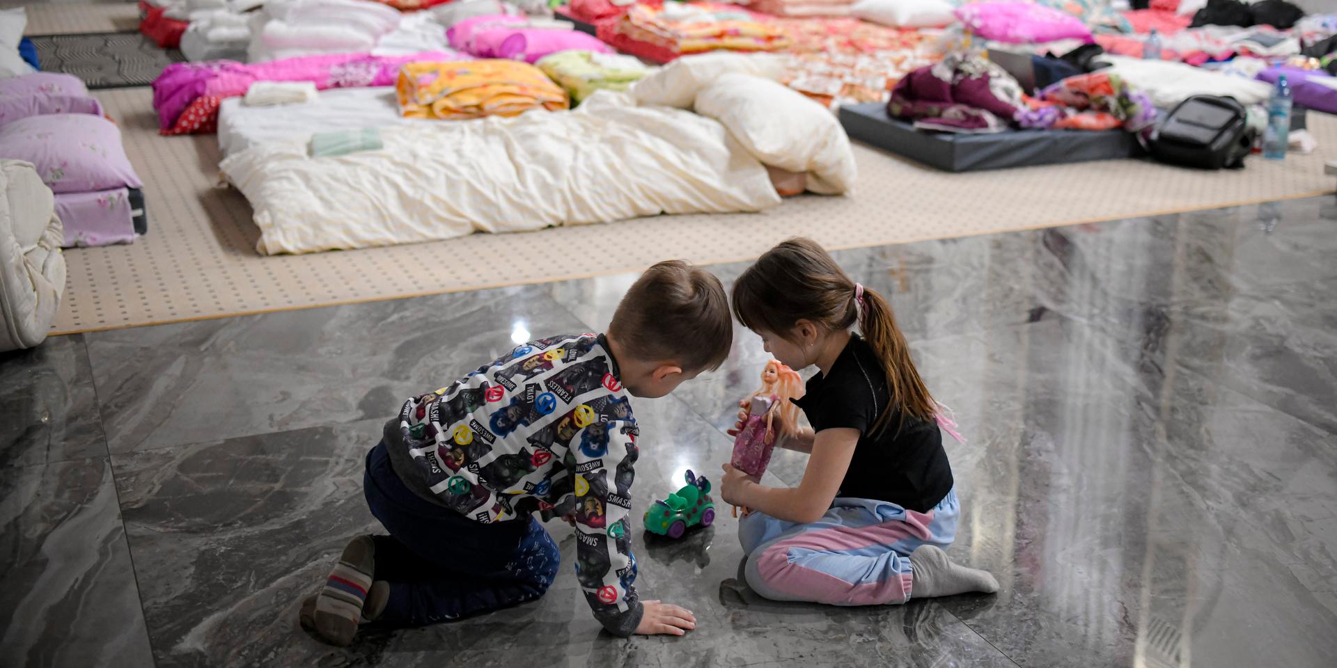 Children who fled the conflict from neighboring Ukraine play on the floor of an event hall in a hotel offering shelter in Siret, Romania, Saturday, Feb. 26, 2022. Romania, which shares around 600 kilometres (372 miles) of borders with Ukraine to the north, is seeing an influx of refugees from the country as many flee Russia's attacks. (AP Photo/Andreea Alexandru)  XAA821